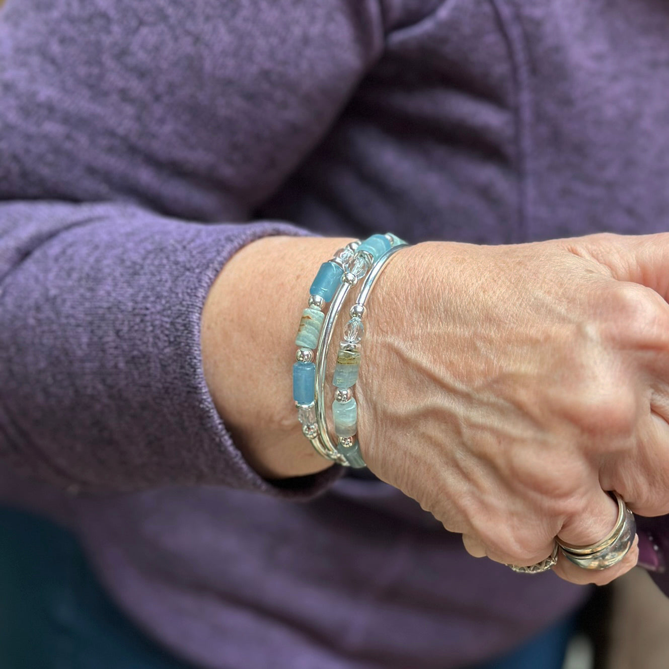 Close-up of a person's wrist wearing multiple bracelets with a blurred background