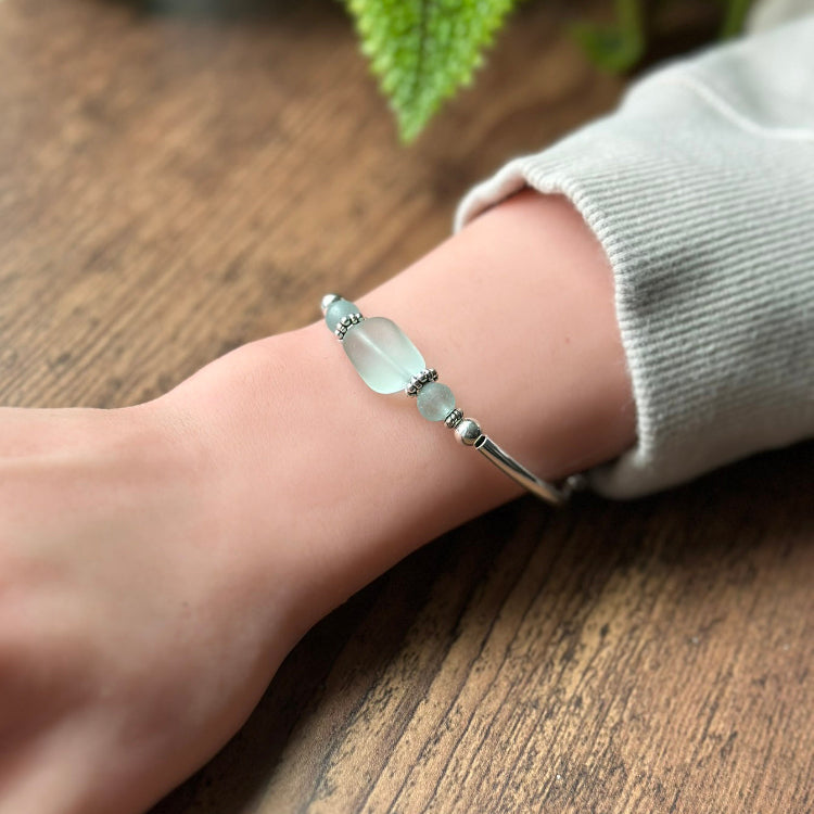 Silver bracelet on a wrist with a wooden background