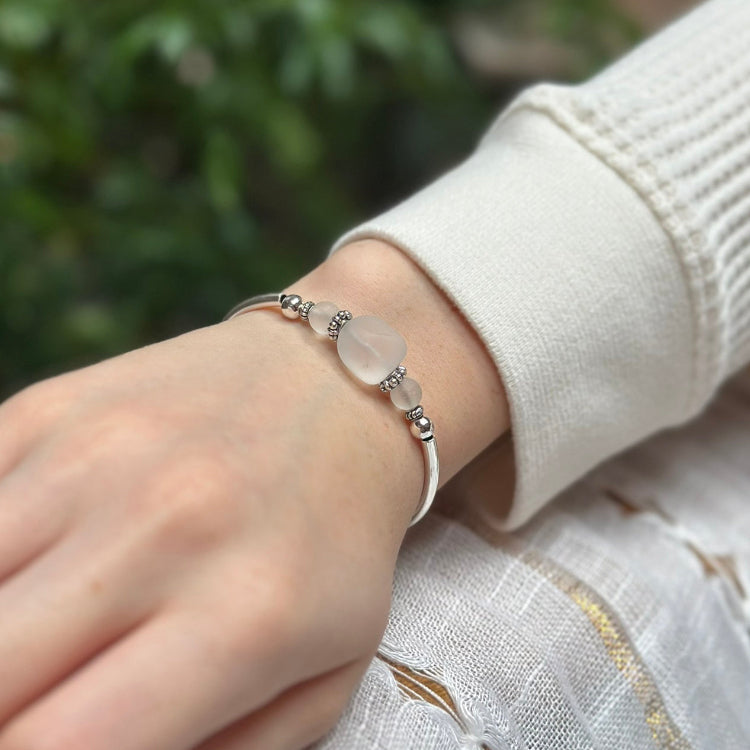 Hand wearing a delicate bracelet with a blurred green background