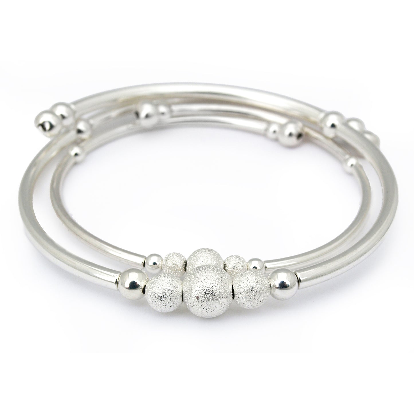 Set of silver bangles with textured beads on a white background