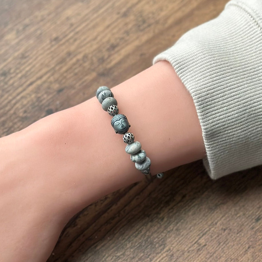 Bracelet with stone beads on a wrist against a wooden background