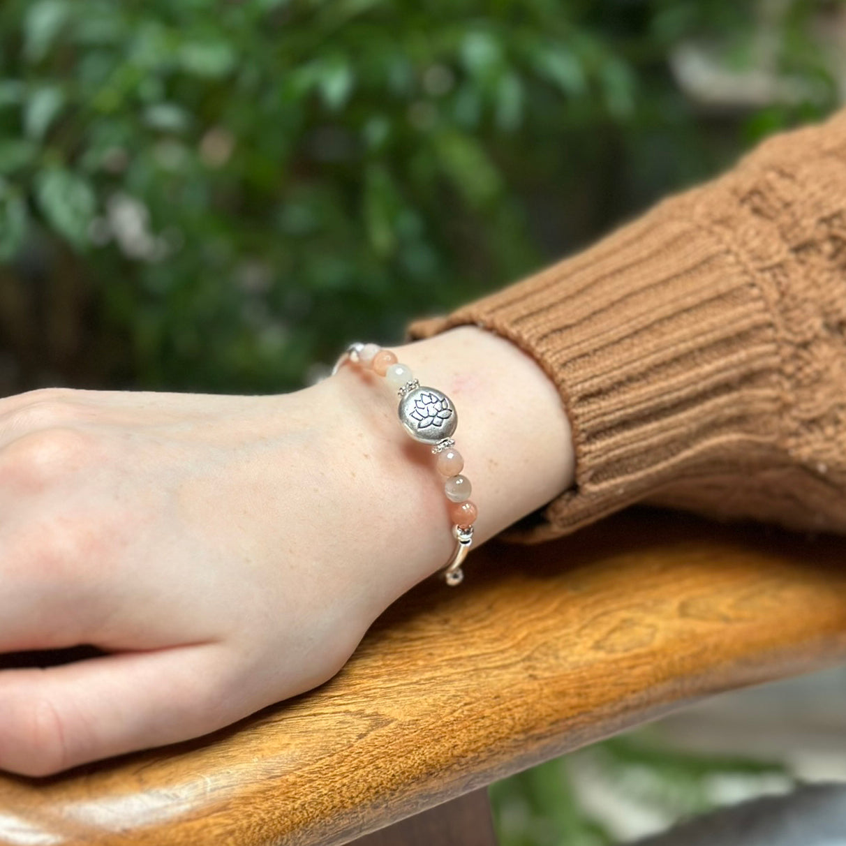 Hand wearing a bracelet with a blurred green background