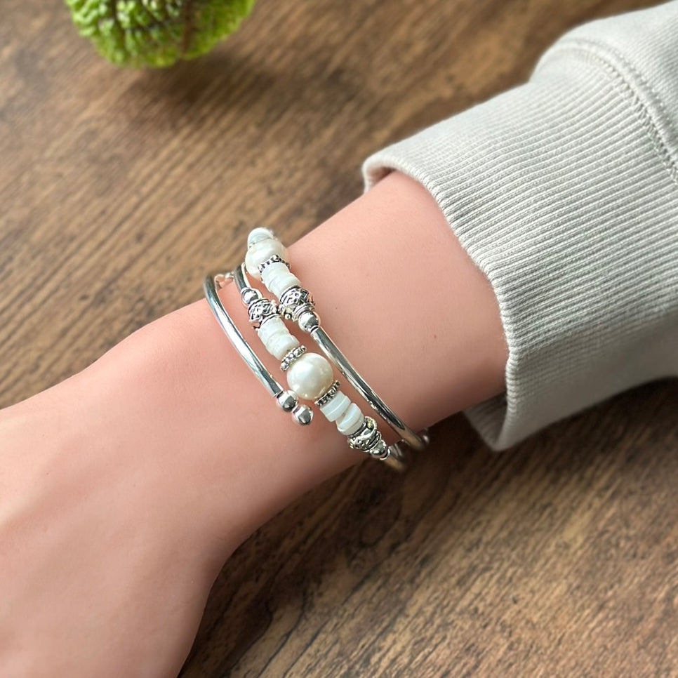 Close-up of a wrist wearing multiple beaded bracelets on a wooden surface