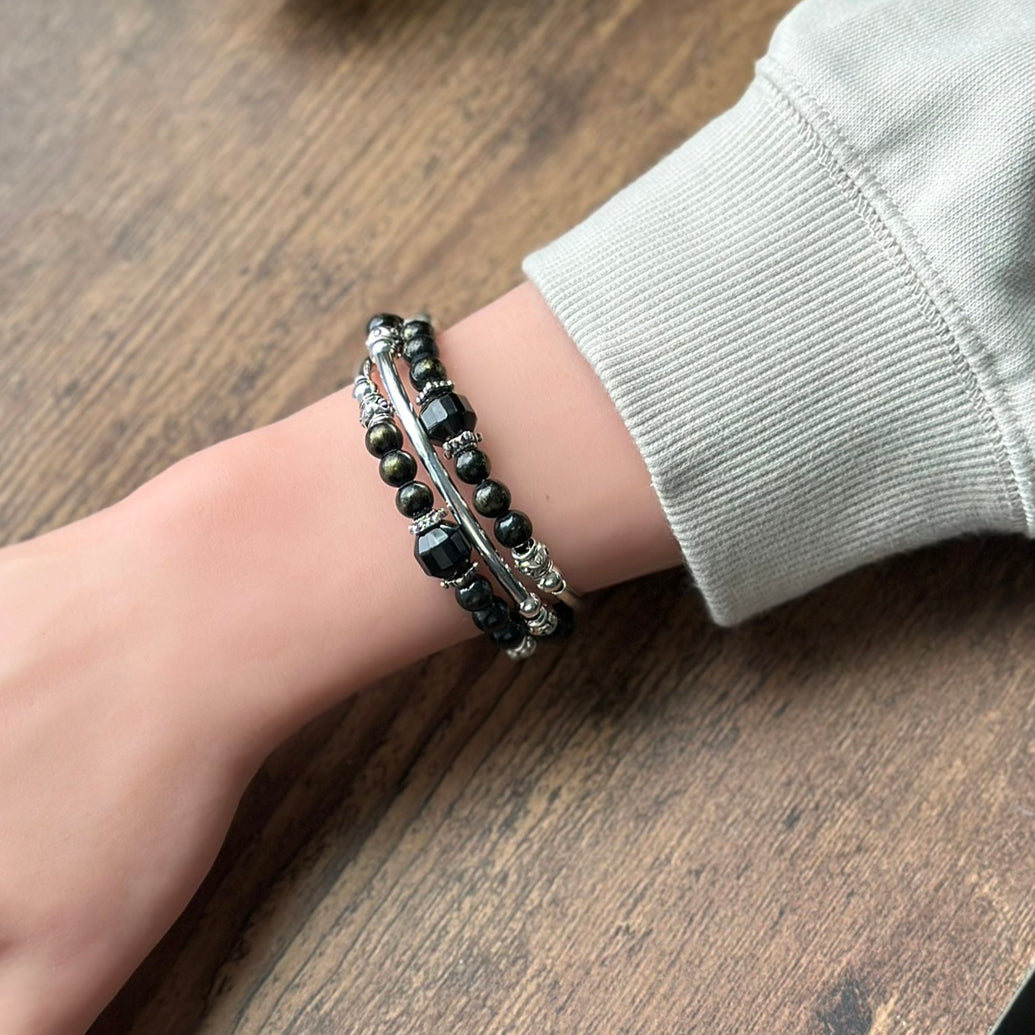Bracelet with black and silver beads on a wrist against a wooden background