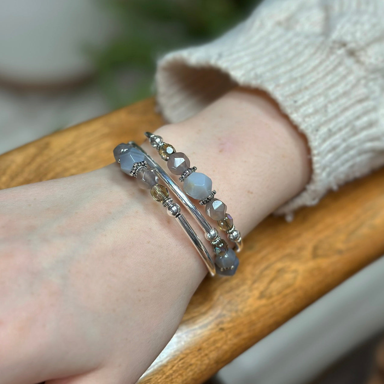 Close-up of a wrist wearing multiple bracelets on a wooden surface