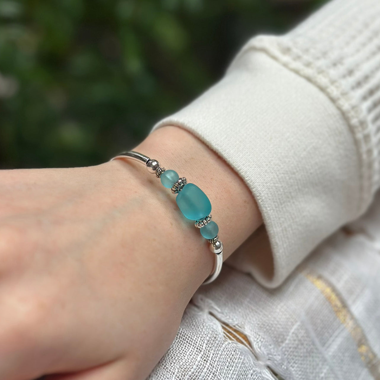 Bracelet with blue beads on a wrist against a blurred green background