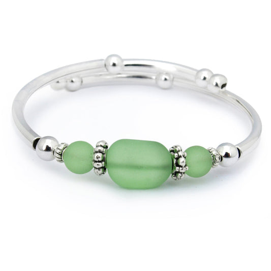 Silver bracelet with green beads on a white background