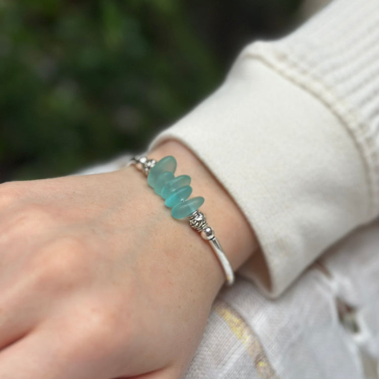 Person wearing a bracelet with blue beads on a blurred natural background