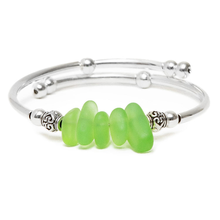 Silver bracelet with green beads on a white background