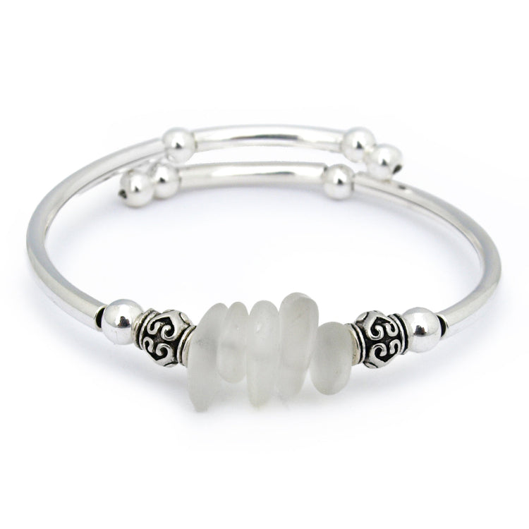 Silver bracelet with a central white bead on a white background