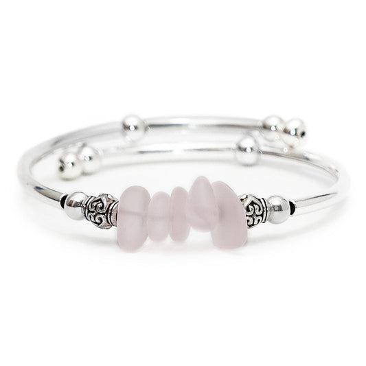 Silver adjustable bangle bracelet featuring stacked sea glass nuggets in pink, accented with decorative silver spacer beads on a clean white background.