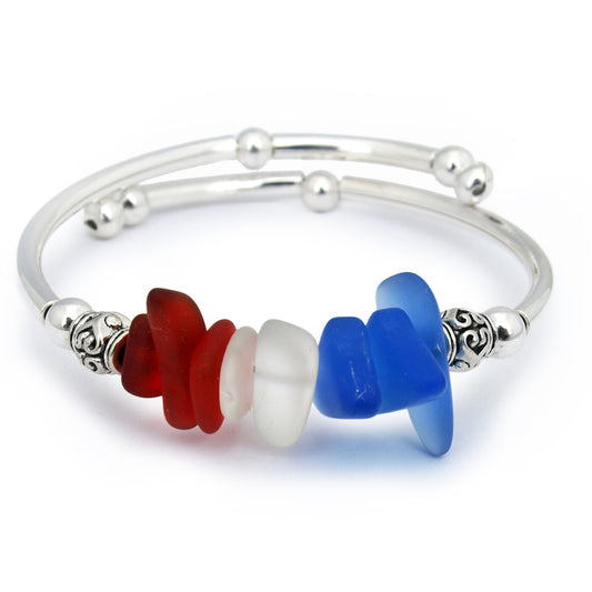 Silver adjustable bangle bracelet featuring stacked sea glass nuggets in red, white, and blue, accented with decorative silver spacer beads on a clean white background.