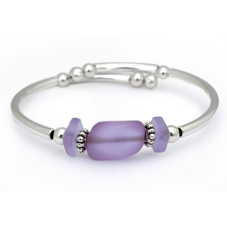 Silver bracelet with a purple bead on a white background