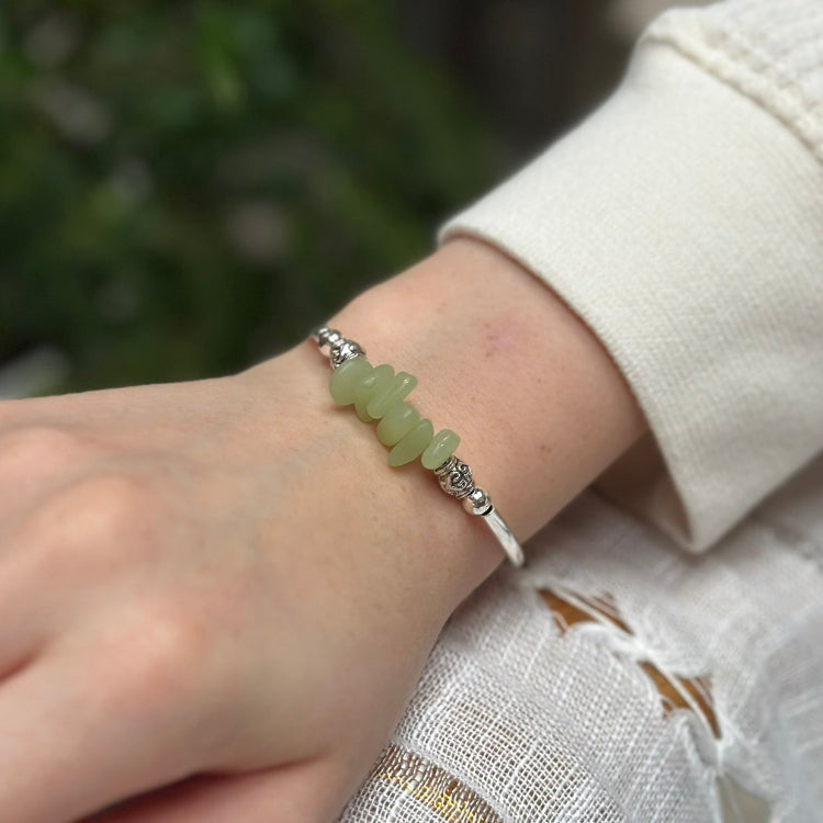 Green beaded bracelet on a wrist with a blurred green background
