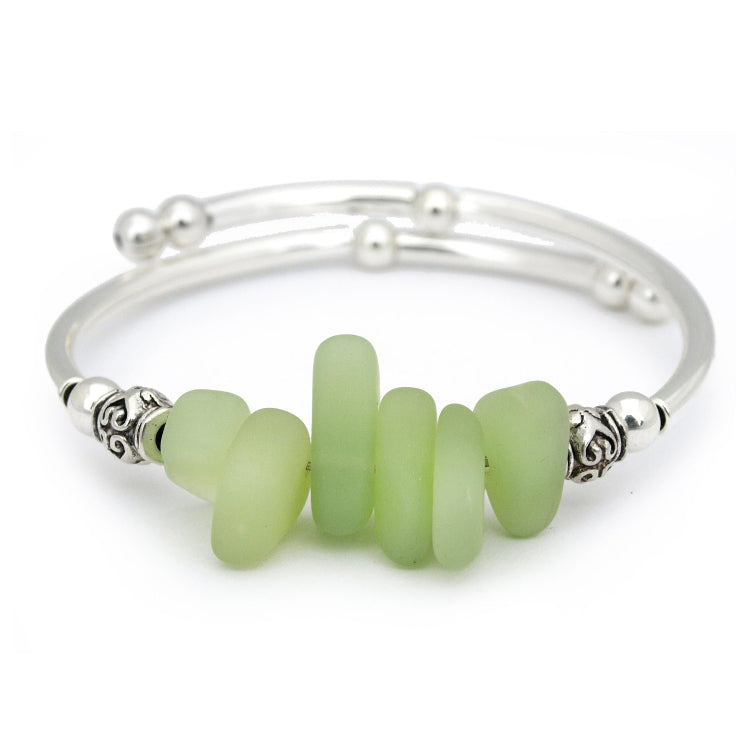 Silver bracelet with green beads on a white background