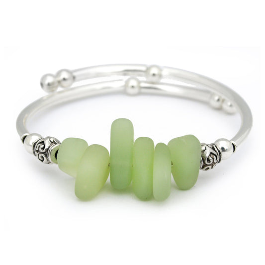 Silver bracelet with green beads on a white background