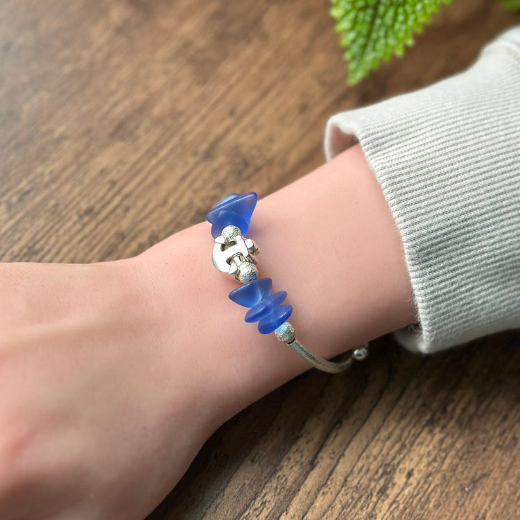 Bracelet with blue and silver beads on a wrist against a wooden background