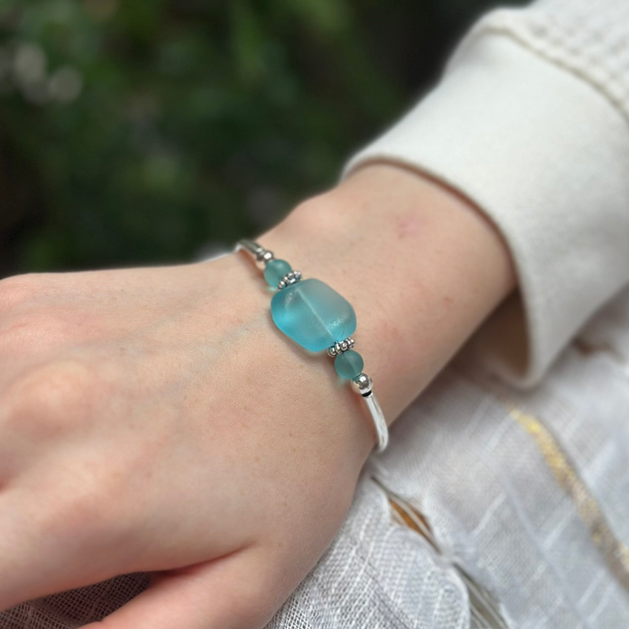 Silver bracelet with frosted aqua blue sea glass bead on a wrist