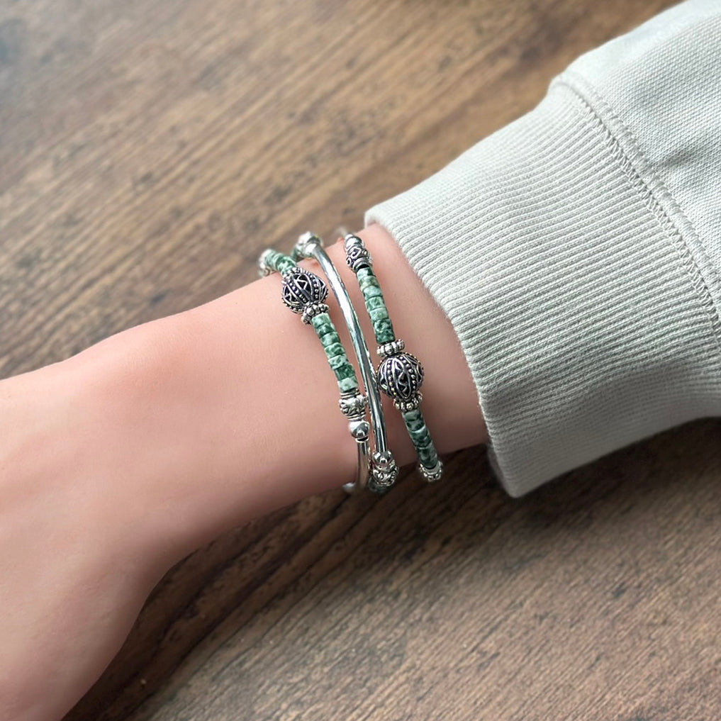 Close-up of a wrist wearing multiple bracelets on a wooden surface
