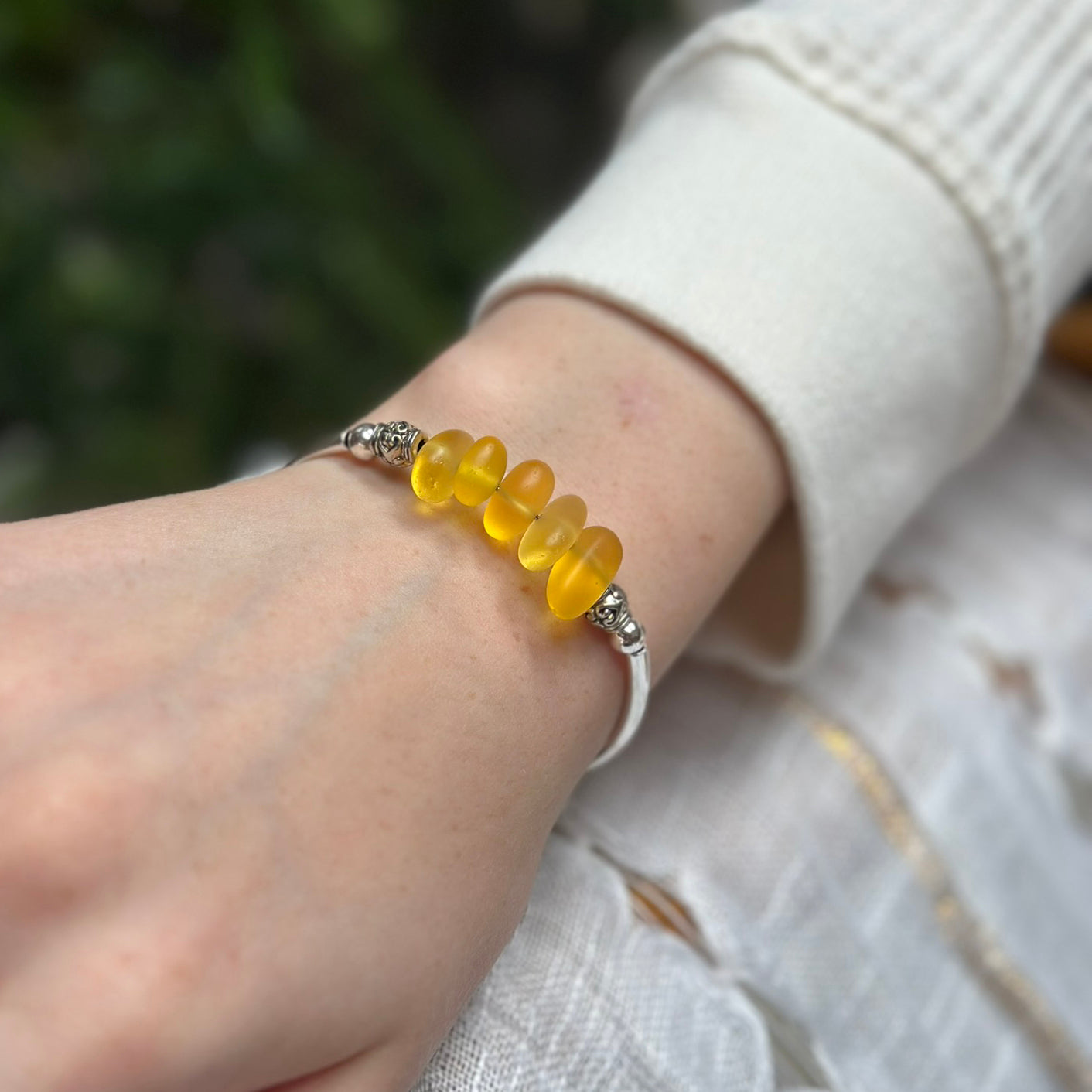Silver bracelet with yellow sea glass beads on a wrist