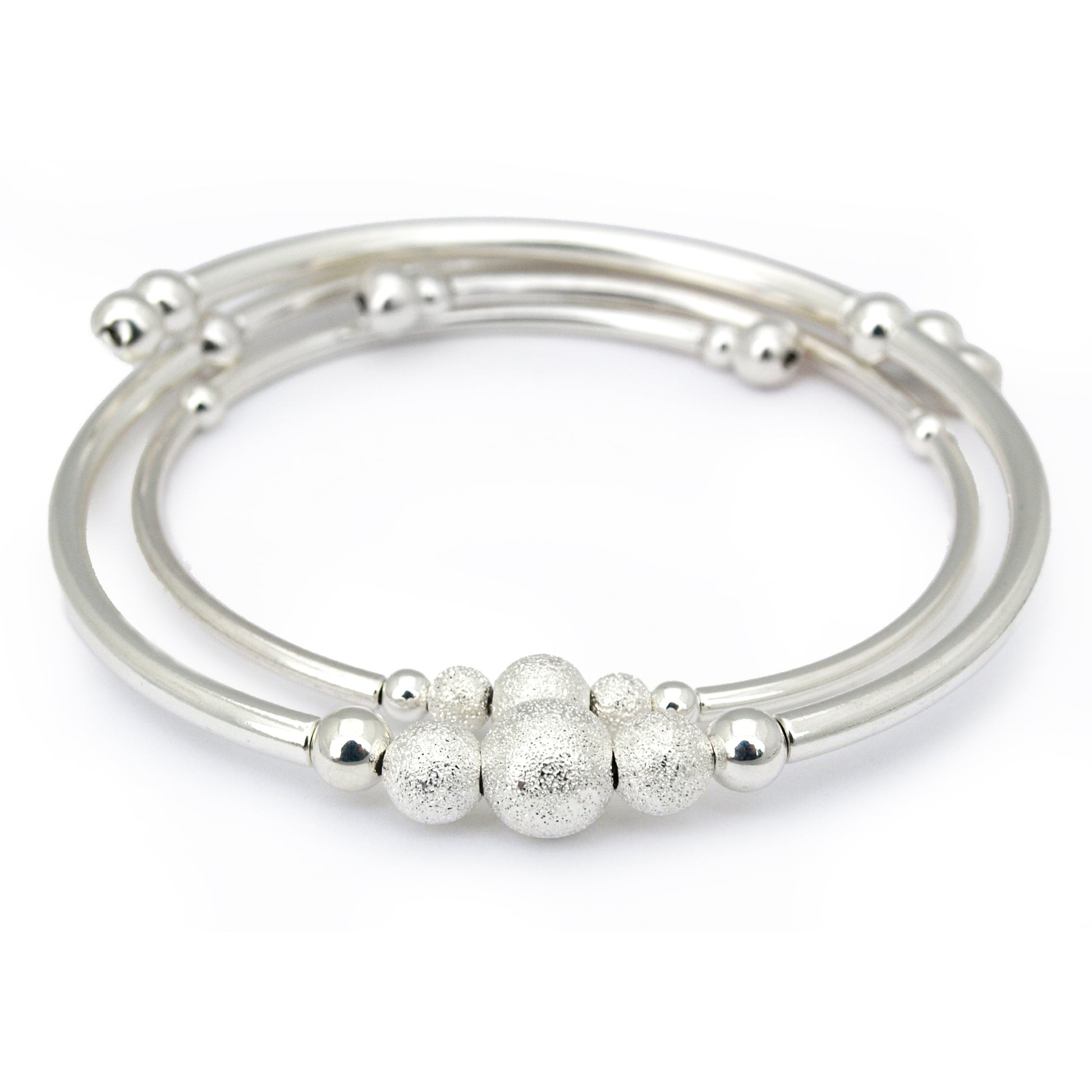 Set of silver bangles with textured beads on a white background