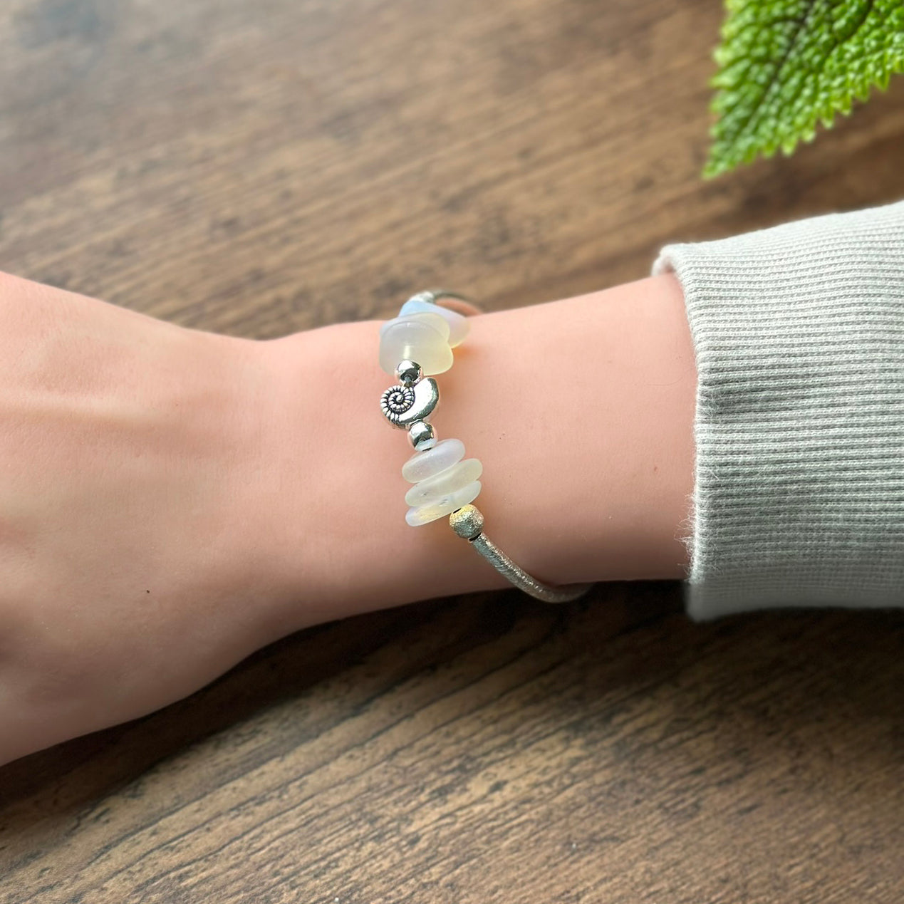 Silver bracelet with opaline sea glass beads and nautilus shell charm on wrist