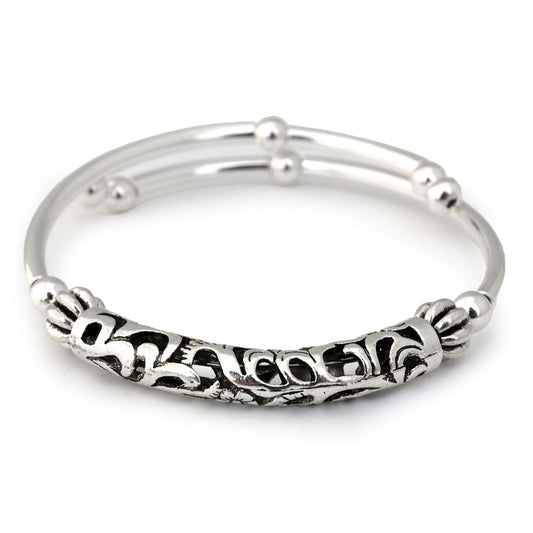 Silver bangle with intricate design on a white background