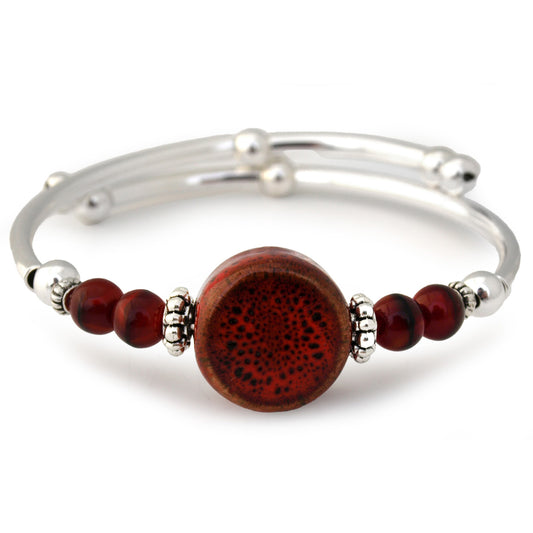 Silver bracelet with a large brown bead and smaller red beads on a white background