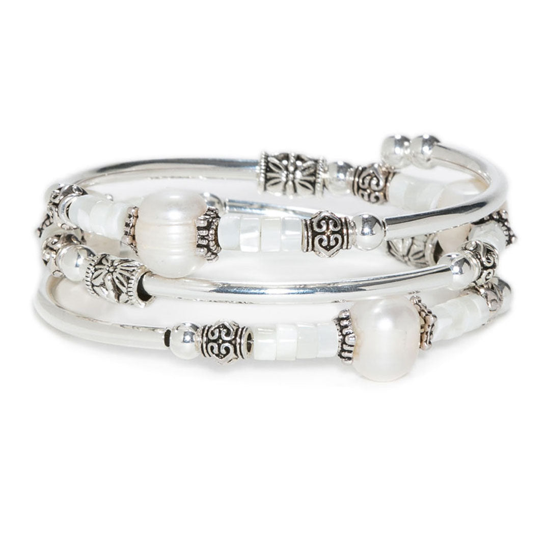 Stack of silver and pearl bracelets on a white background