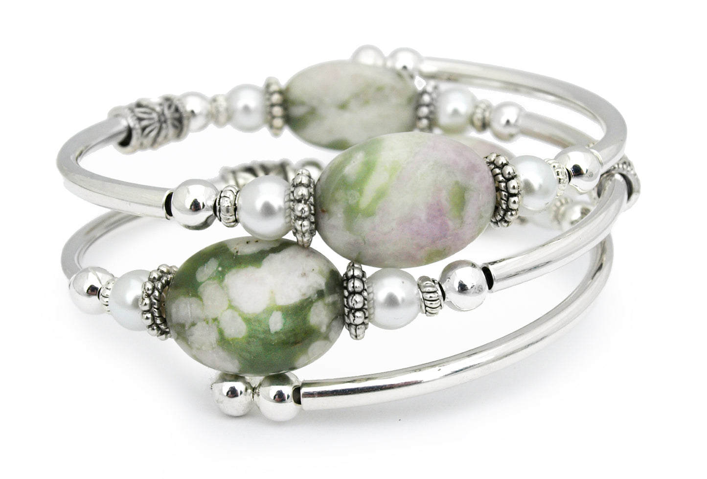 green, cream, and salmon colored oval gemstone on a silver bangle bracelet with white pearl accents, placed on a white background